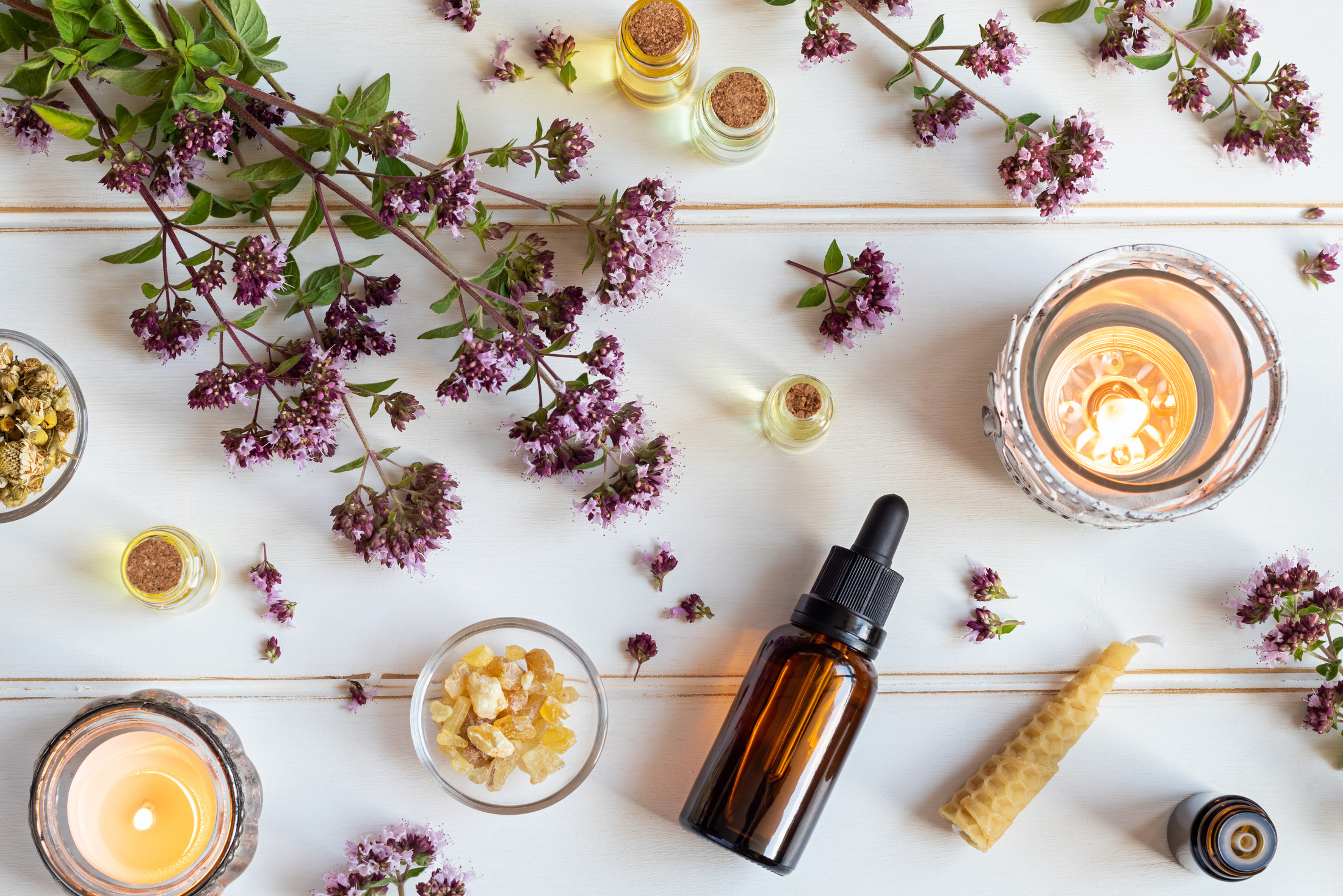 Bottles Of Essential Oil With Blooming Oregano, Frankincense And